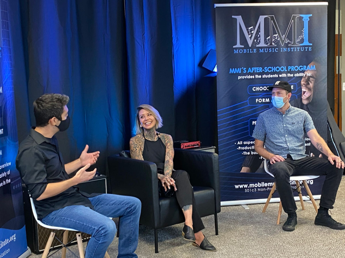 A panel discussion at the Mobile Music Institute music nonprofit, with speakers seated in front of an MMI banner.