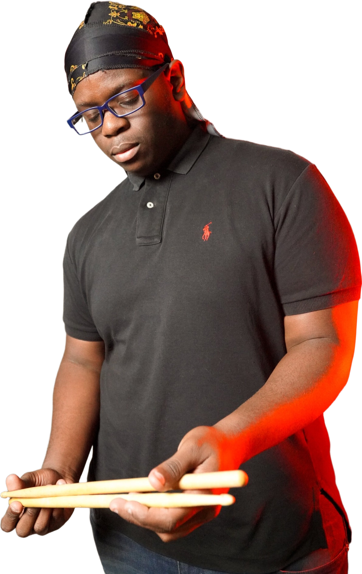 Student musician standing near a red light, looking down at drumsticks.