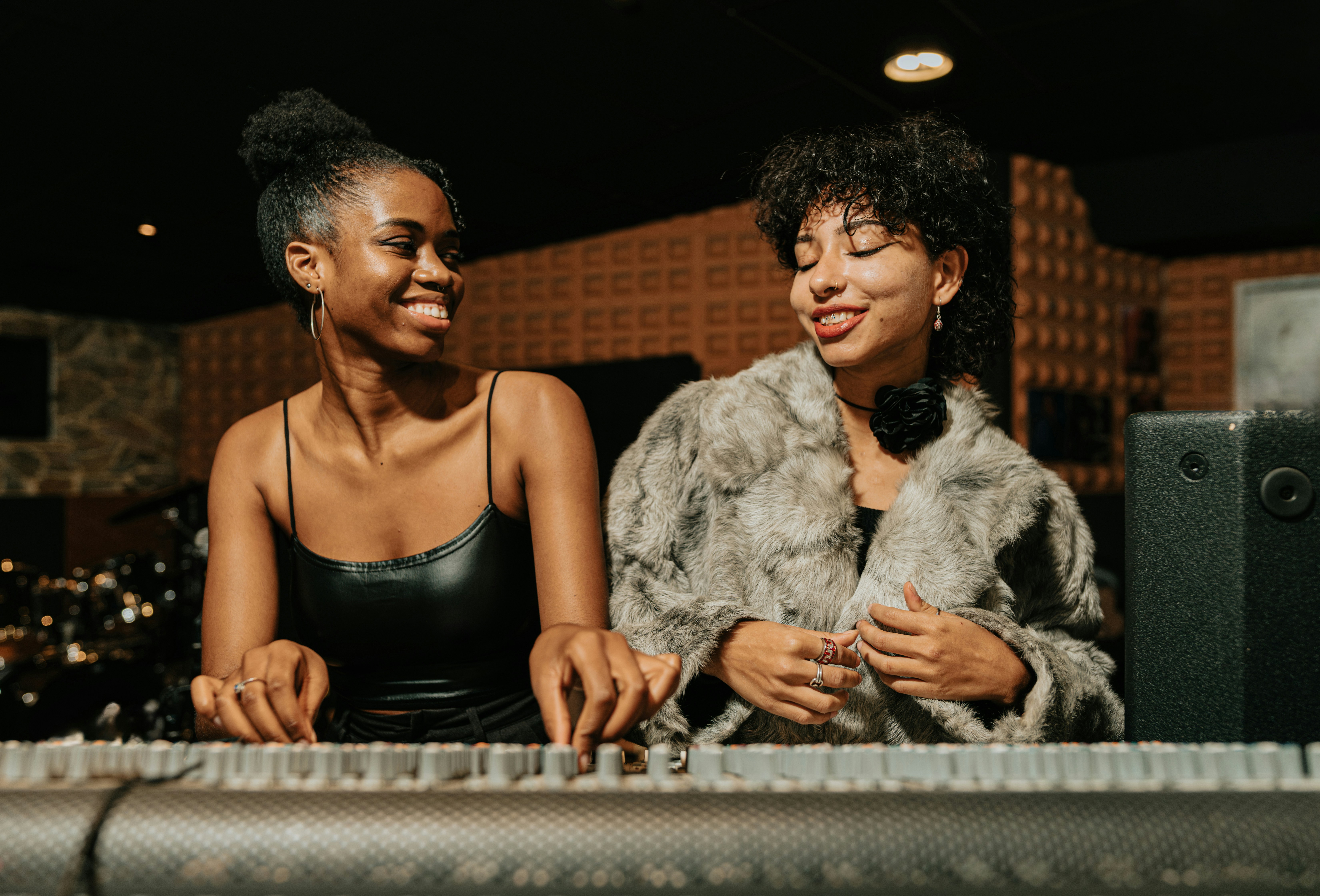 Two young musicians sitting together at a studio keyboard during a collaborative session.